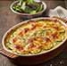 Gratin de courgettes sortant du four accompagné d'une salade dans un bol