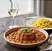 Osso Buco de Veau dans une assiette servie avec un polenta et un verre de vin blanc