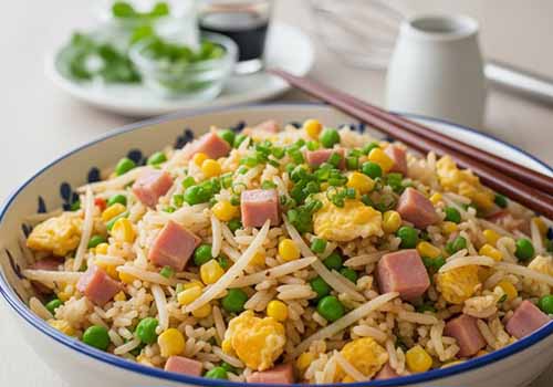 Riz Cantonais servi dans une assiette creuse avec des baguettes chinoises