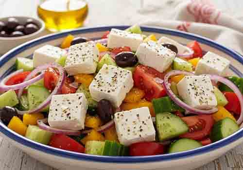 Salade Grecque composée de concombre, tomates, poivrons, oignon rouge, olives noires et feta