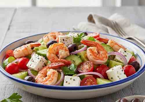 Salade Grecque aux Crevettes composée de concombre, tomates cerise, oignon rouge, olives noires et feta.