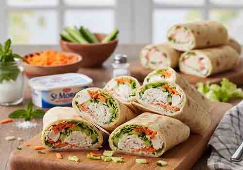 Wraps nappés de fromage frais et composés de poulet effiloché, carotte, concombre et de laitue.